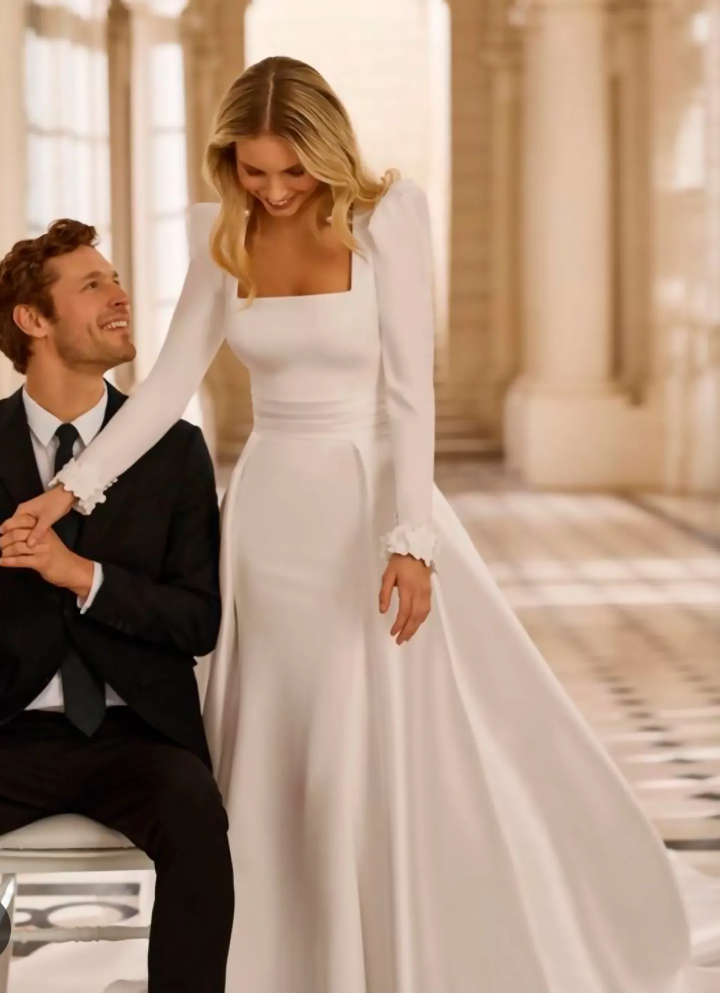 Novio sentado junto a la novia con vestido de manga larga